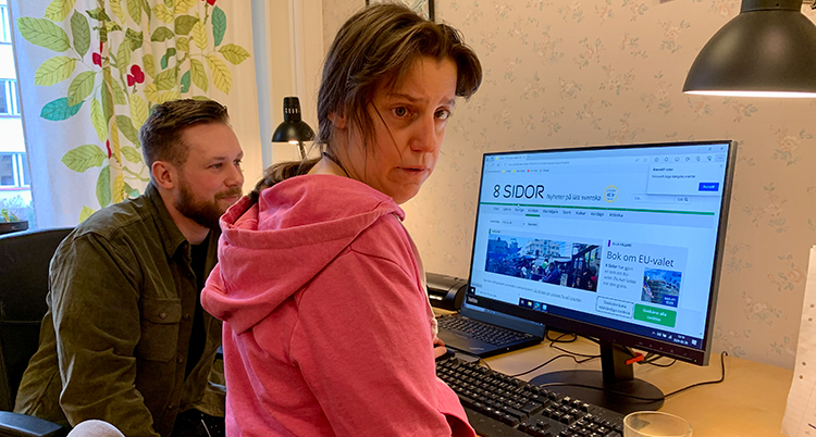 Hon sitter framför en dator. På datorn syns 8 Sidors sida.