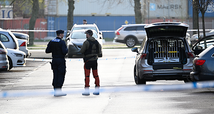 Två poliser står och pratar på en parkeringsplats.