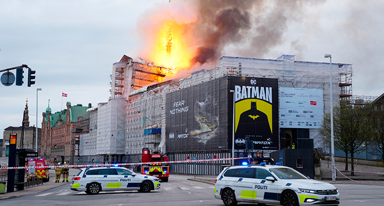 Ett stor hus med polisbilar framför. En stor brand syns på andra sidan huset.