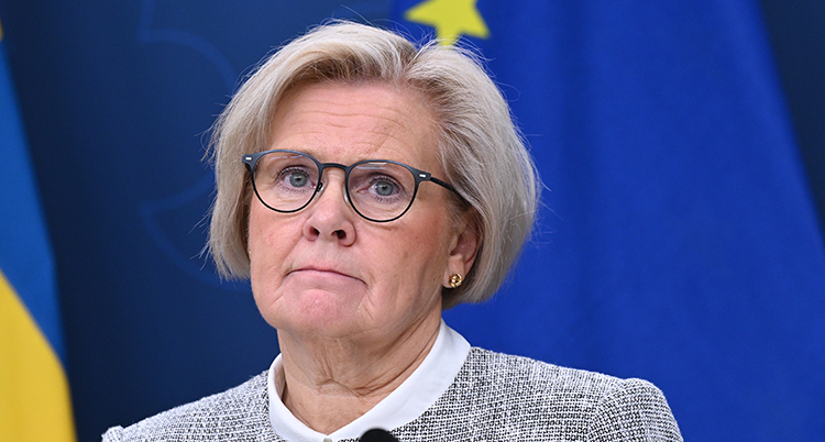 Hon har kort ljust hår och glasögon.