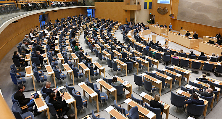 Politiker som sitter i sina bänkar i en stor sal.