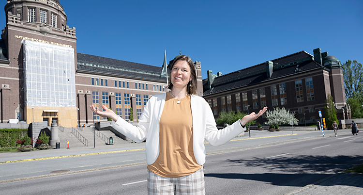 Hon står utanför museet. Hon ser glad ut.