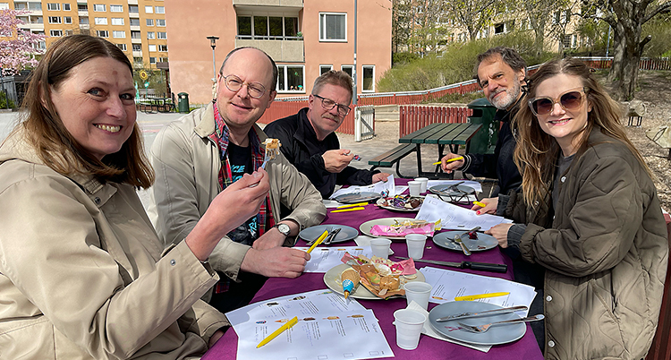Fem personer i redaktionen sitter vid ett bord utomhus med glassar. De ser glada ut.