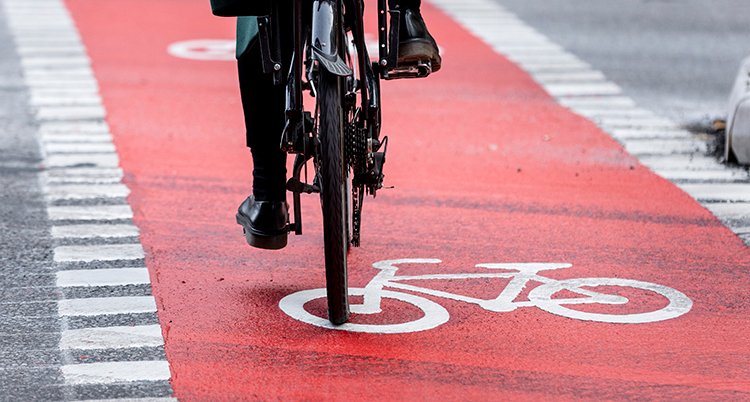 En cykelbana som är målad i rött. En cyklist syns lite.