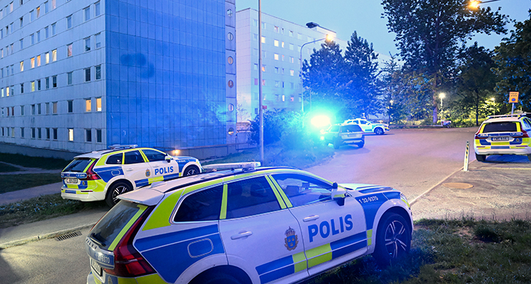 Polisbilar står vid ett flervåningshus.