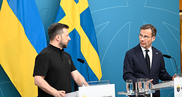 De står bredvid varandra och talar på en scen.