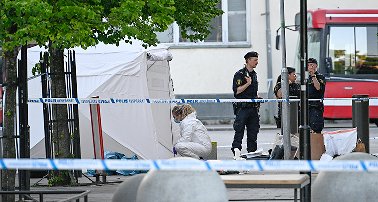 Fyra poliser står vid en busshållplats i Farsta centrum.