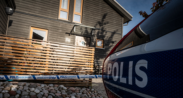 En polisbil vid en uppfart till ett hus.