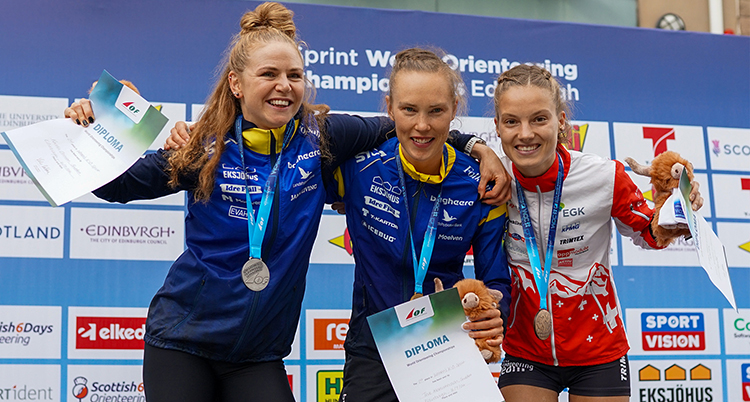 De är glada och har medaljer och diplom. De håller armarna om varandras axlar.