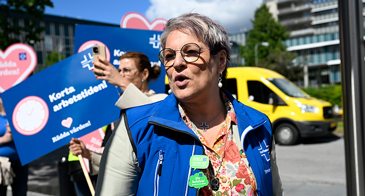 Ribeiro pratar. Bakom hennes syns personer med skyltar om strejken.