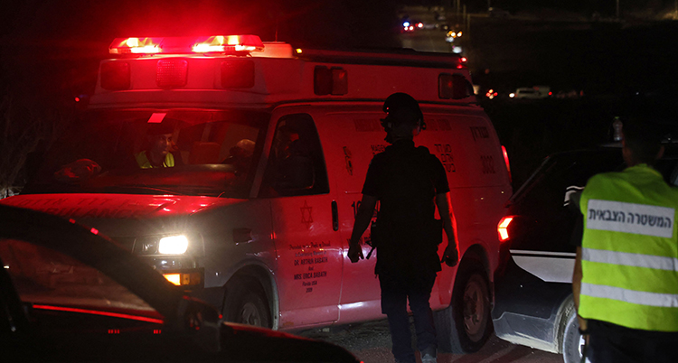 En person står framför en ambulans. Det lyser rött.