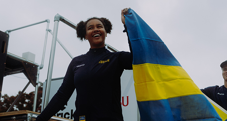 Hon håller upp en svenska flagga. Hon är glad.