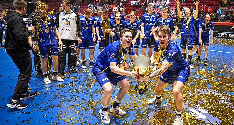 Två glada spelare håller upp en pokal. Bakom dem står flera andra glada spelare.