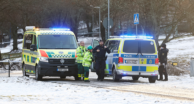 En ambulans och en polisbil med poliser och sjukvårdare utanför.