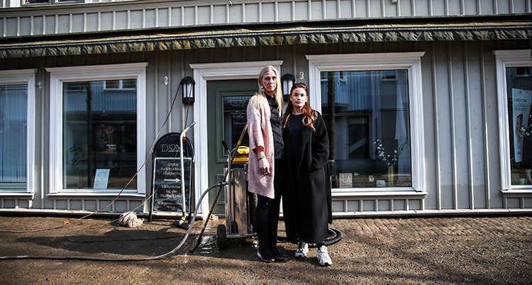 De står utanför huset. Marken är lerig efter allt vatten.