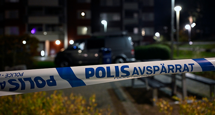 Ett polisband över en väg bland hus på kvällen.