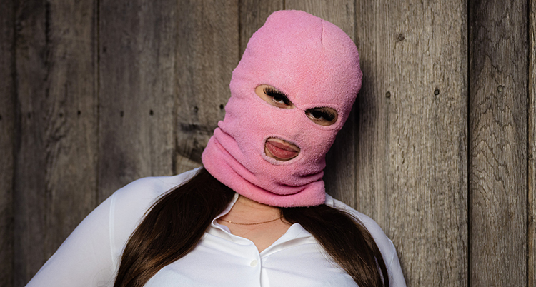 Hon har en mask över hela ansiktet. Hon står framför en väg.