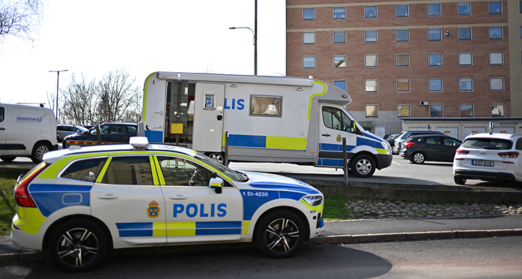 Två polisbilar står vid en vägg.