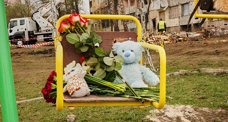 Blommor och en nalle sitter på en gunga.