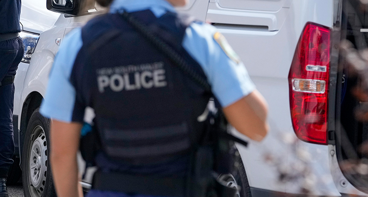 En rygg på en polis. Det står police på polisens väst.