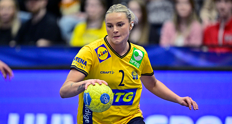 Hon har svenska landslagets kläder. Hon håller i en boll.