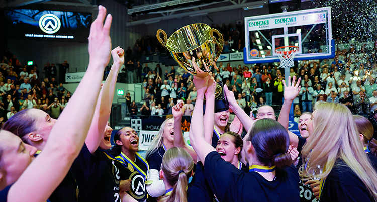 De står nära varandra på planen och sträcker upp armarna och en pokal.