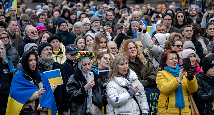 Många står tillsammans. En del har Ukrainas flagga.
