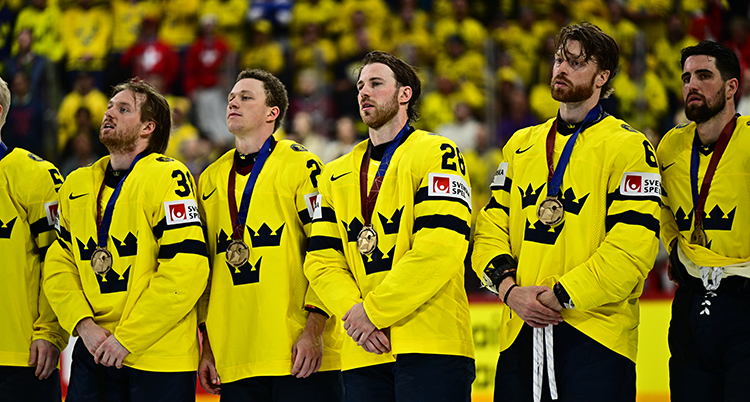 Ishockeyspelare står bredvid varandra med medaljer runt halsen.