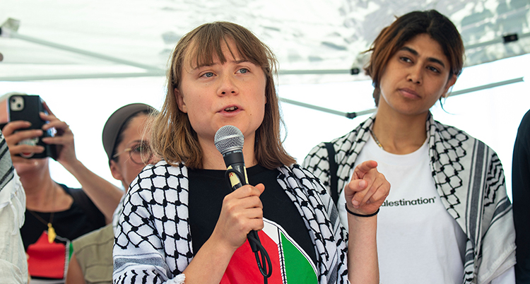 Hon pratar i en mikrofon. Hon har palestiniernas sjal på sig.