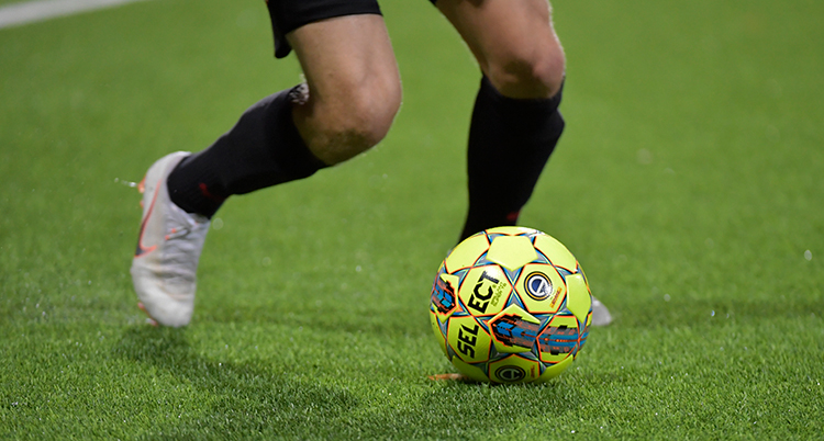 Närbild på ett par ben som spelar fotboll på en grön matta.