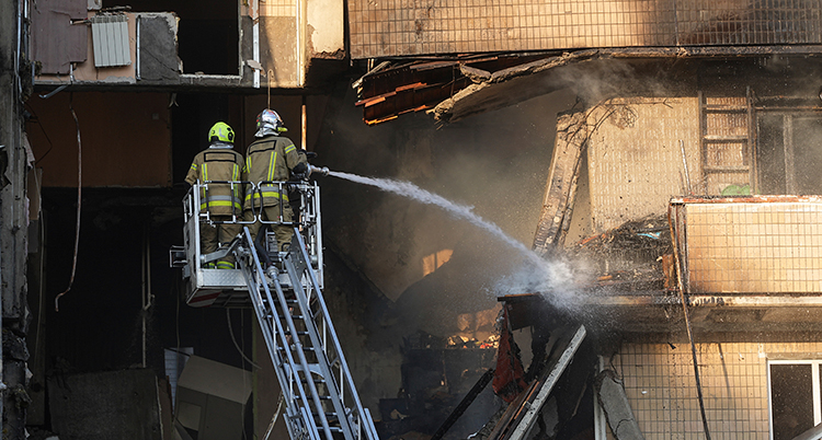 De sprutar vatten mot ett hus som är förstört.