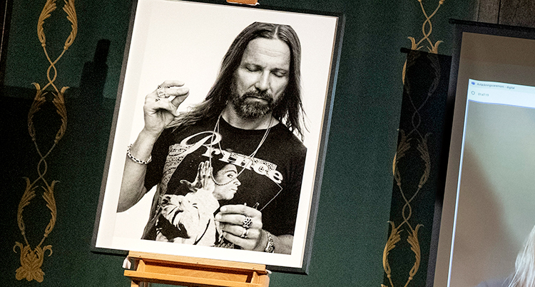 Bilden visar en tavla som står på ett staffli. Tavlan är ett fotografi av låtskrivaren Max Martin. Fotot är svartvitt.