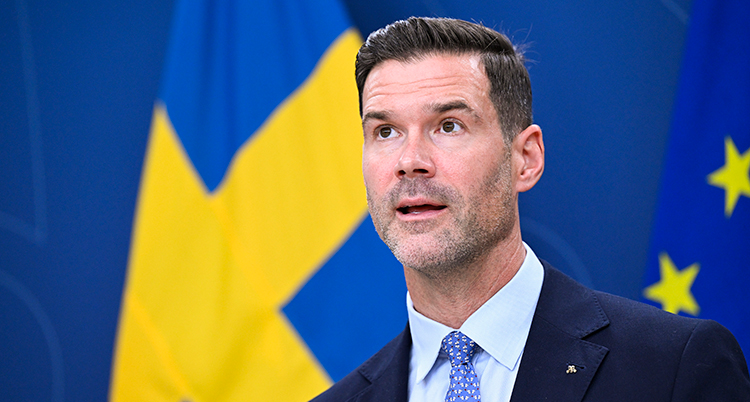 Han står framför svenska flaggor.