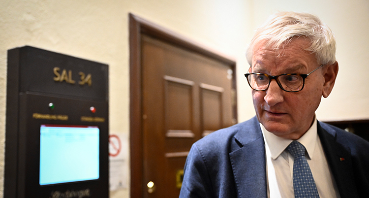 Han har kostym och glasögon.