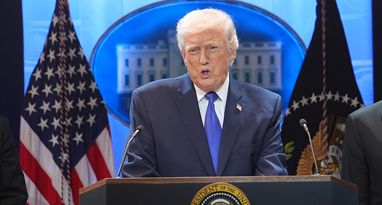 Donald Trump står i en talarstol. Han pratar i en mikrofon. Bakom syns USAs flagga.
