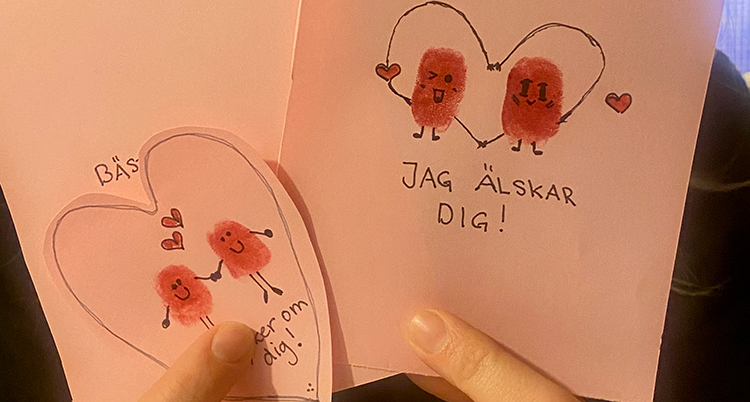 En hand håller i kort av rosa papper.
