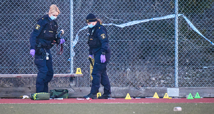 Två kvinnliga poliser med munskydd jobbar vid en brottsplats.
