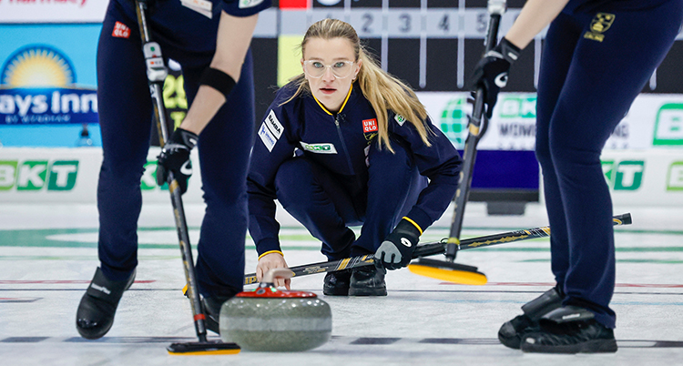 Hon tittar efter stenen som hon just puttat iväg. Benen på två andra spelare syns.