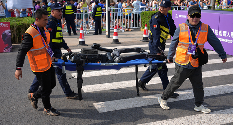 Fyra personer bär roboten på en bår.