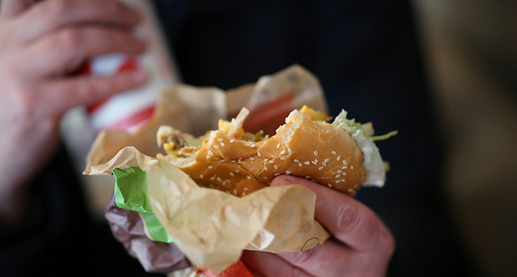 En hand håller i en hamburgare.