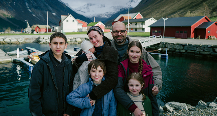 Två vuxna står med fem barn. Bakom dem syns en fjord.