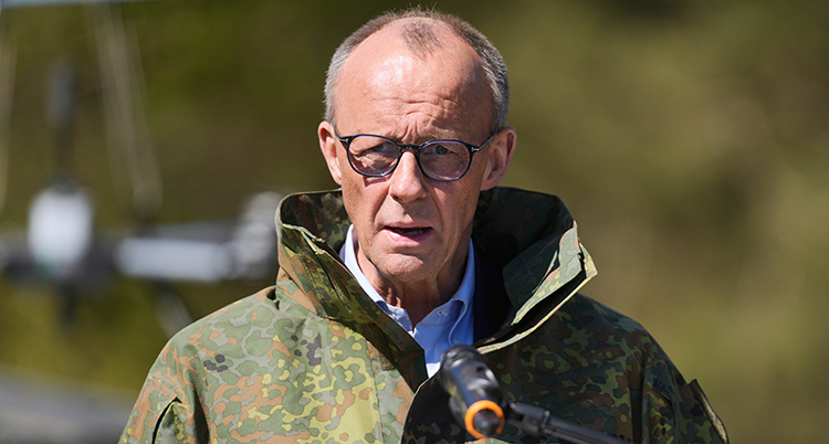 Han har glasögon och en jacka i militärernas färger.
