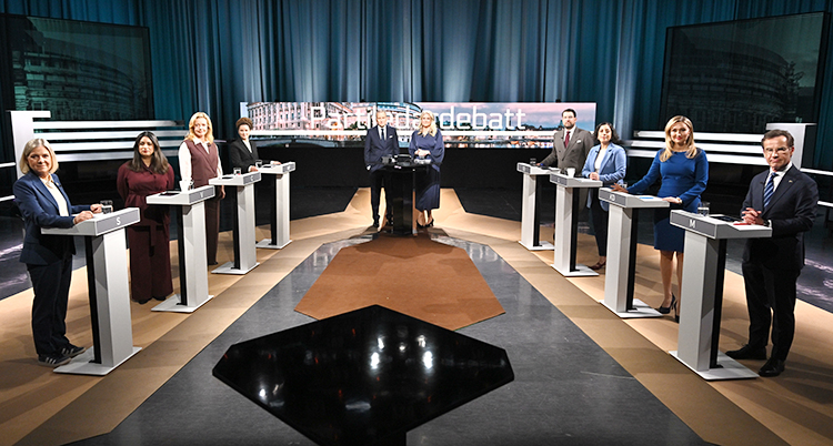 De åtta partiledarna står i en tv-studio. Där står också två programledare.