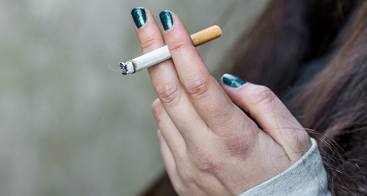 Närbild på en hand som håller en cigarett.