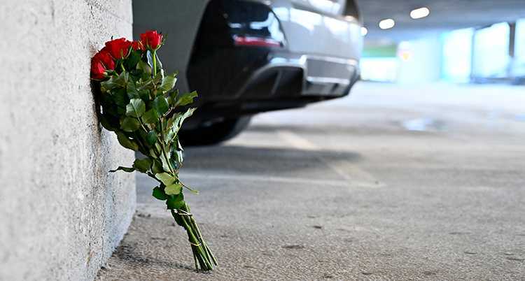 En bukett med blommor i ett garage. En bil syns i bakgrunden.
