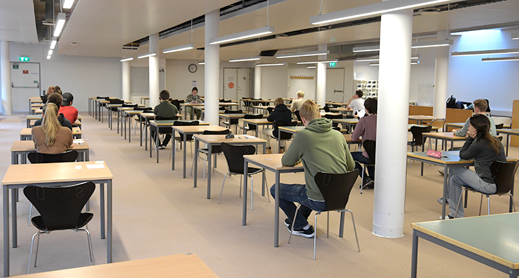 Ungefär 15 personer sitter i en stor sal. De sitter vid varsin bänk och skriver prov.