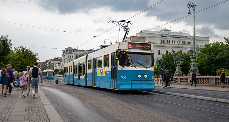 En spårvagn kör på gatan. Folk går vid sidan om.