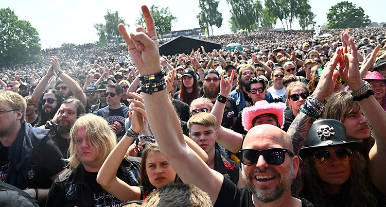 Massor av människor står vid en scen och lyssnar på ett band.