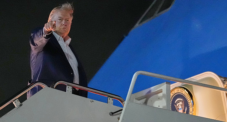 Donald Trump på väg in i ett flygplan. Han pekar med sitt pekfinger.