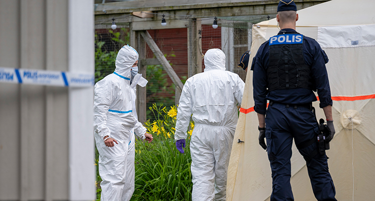 Två vitklädda personer och en polis vid ett hus.